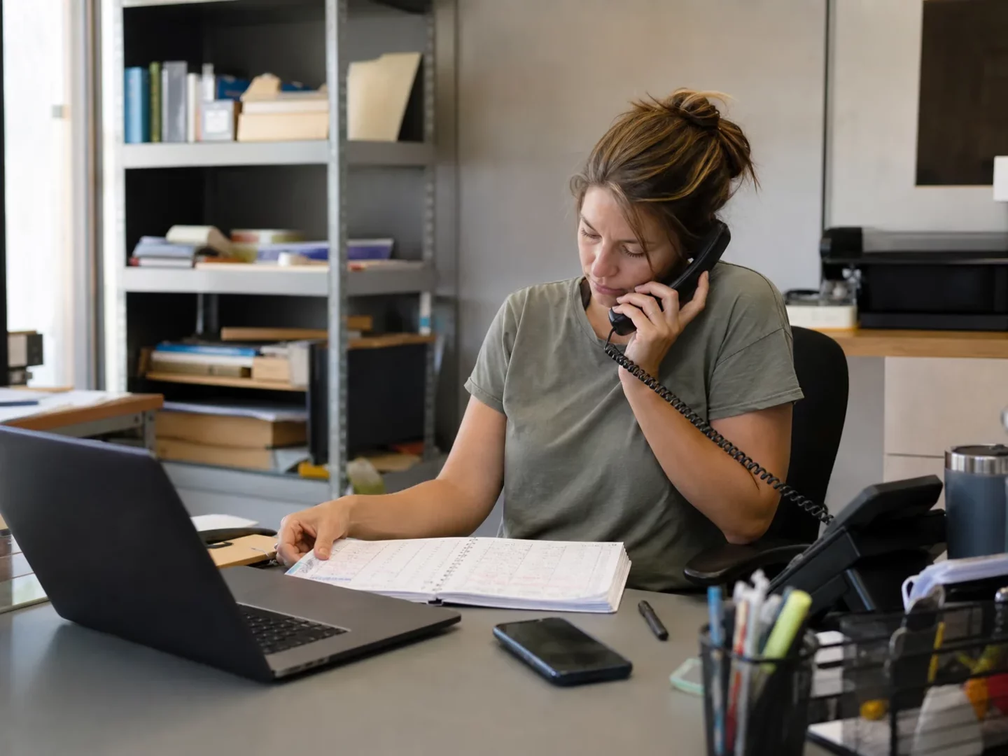 Receptionist checking a schedule while taking a customer call