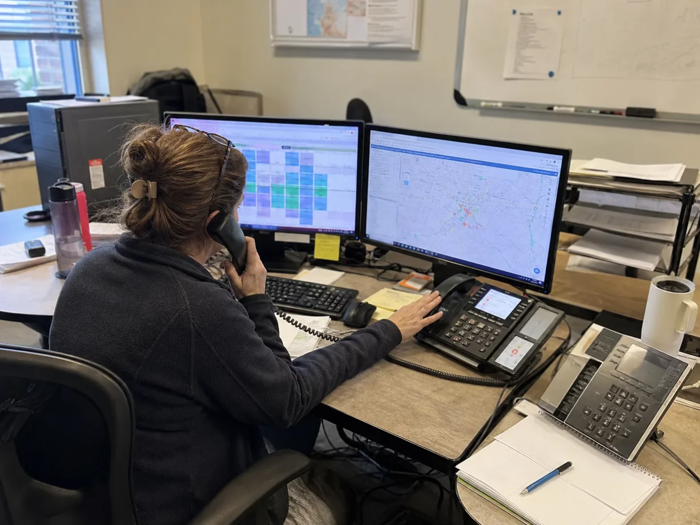 Service dispatcher handling incoming calls beside a technician schedule