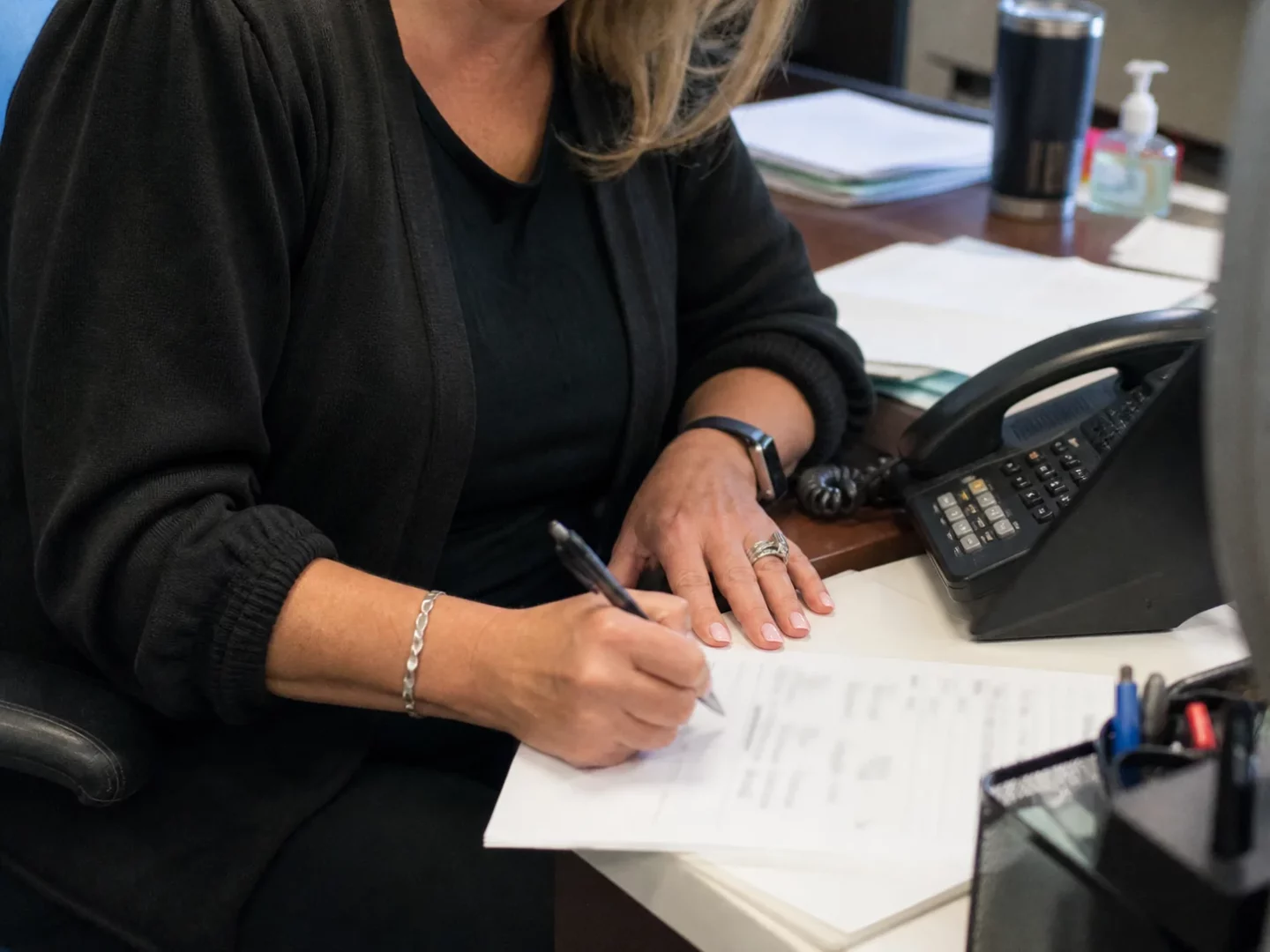 Receptionist recording caller details beside a desk phone